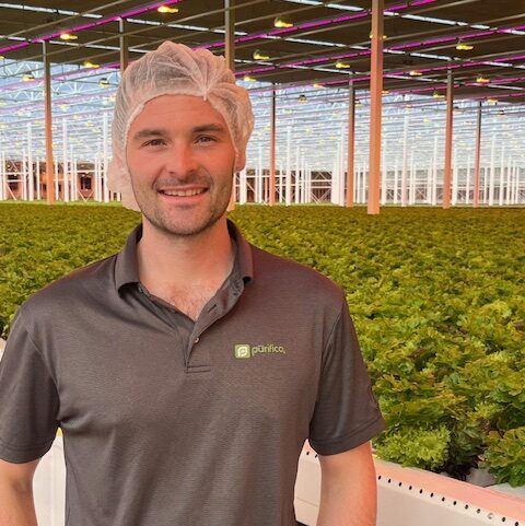 man standing in front of a giant farm facility