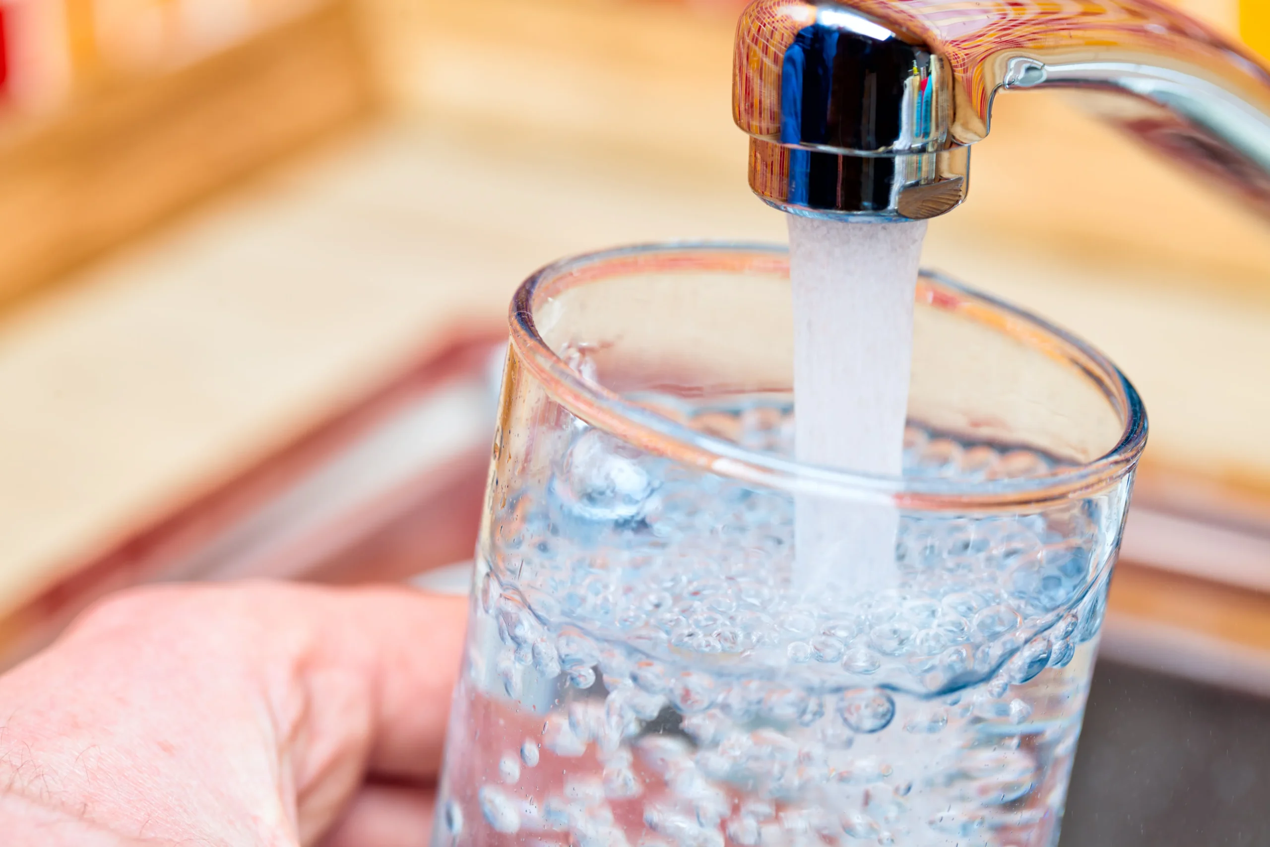 person using a faucet to fill up a glass with clean water