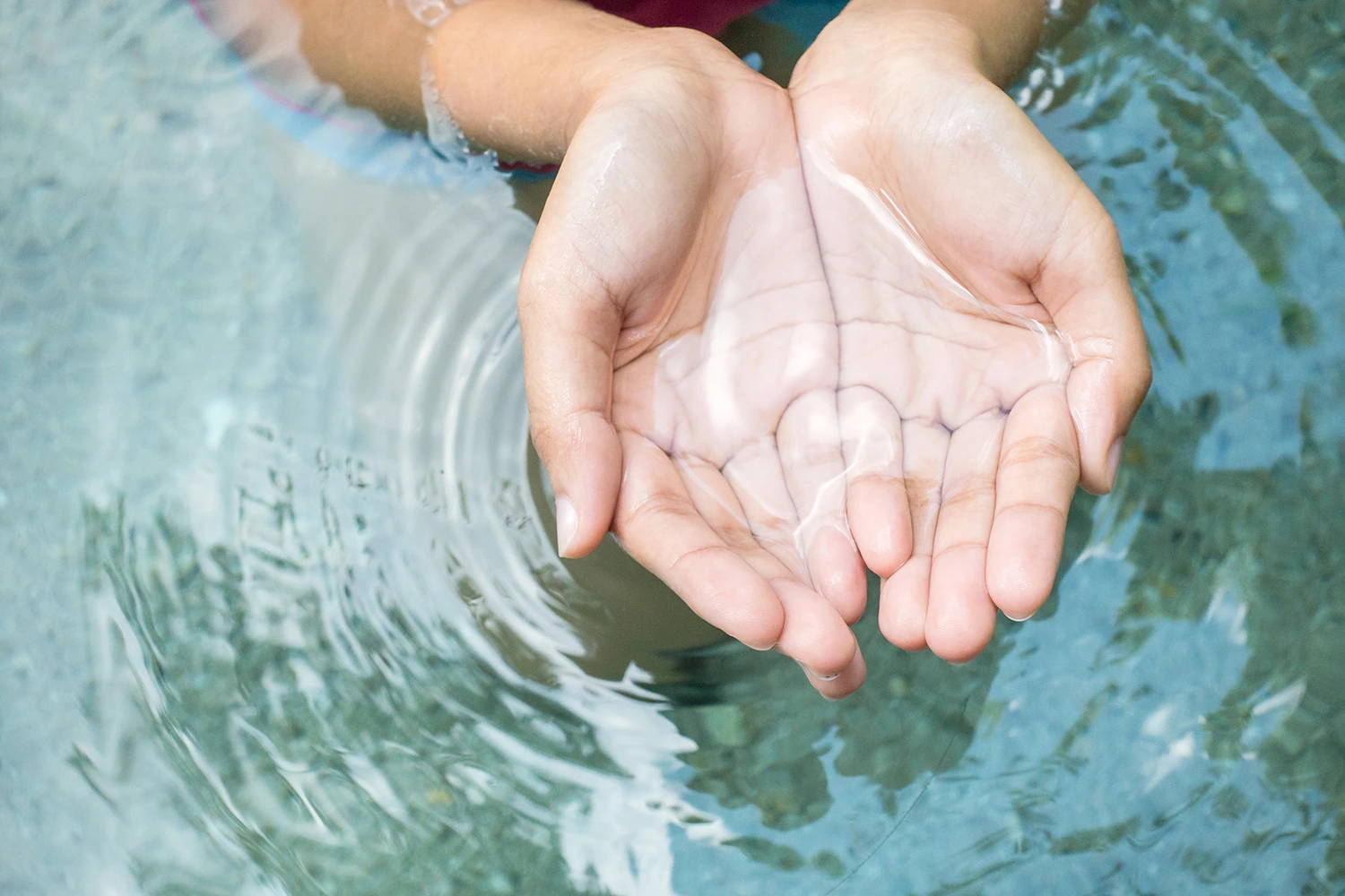 person scooping up some water with their hands