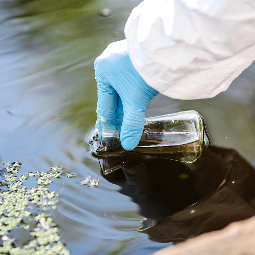 scientist filling up a vial of dirty water to test