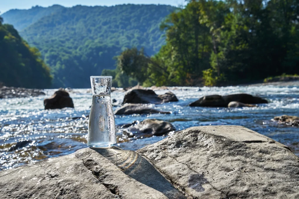 a river with a glass jar holding some of the lean water in it