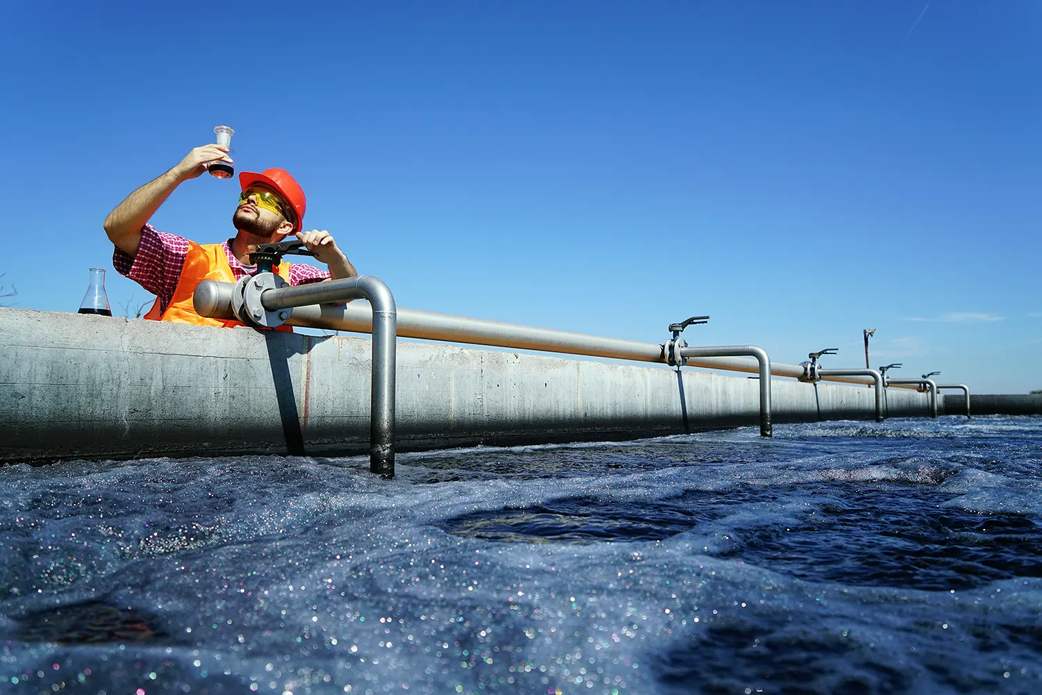 man looking at a vial of water at a water treatment plant