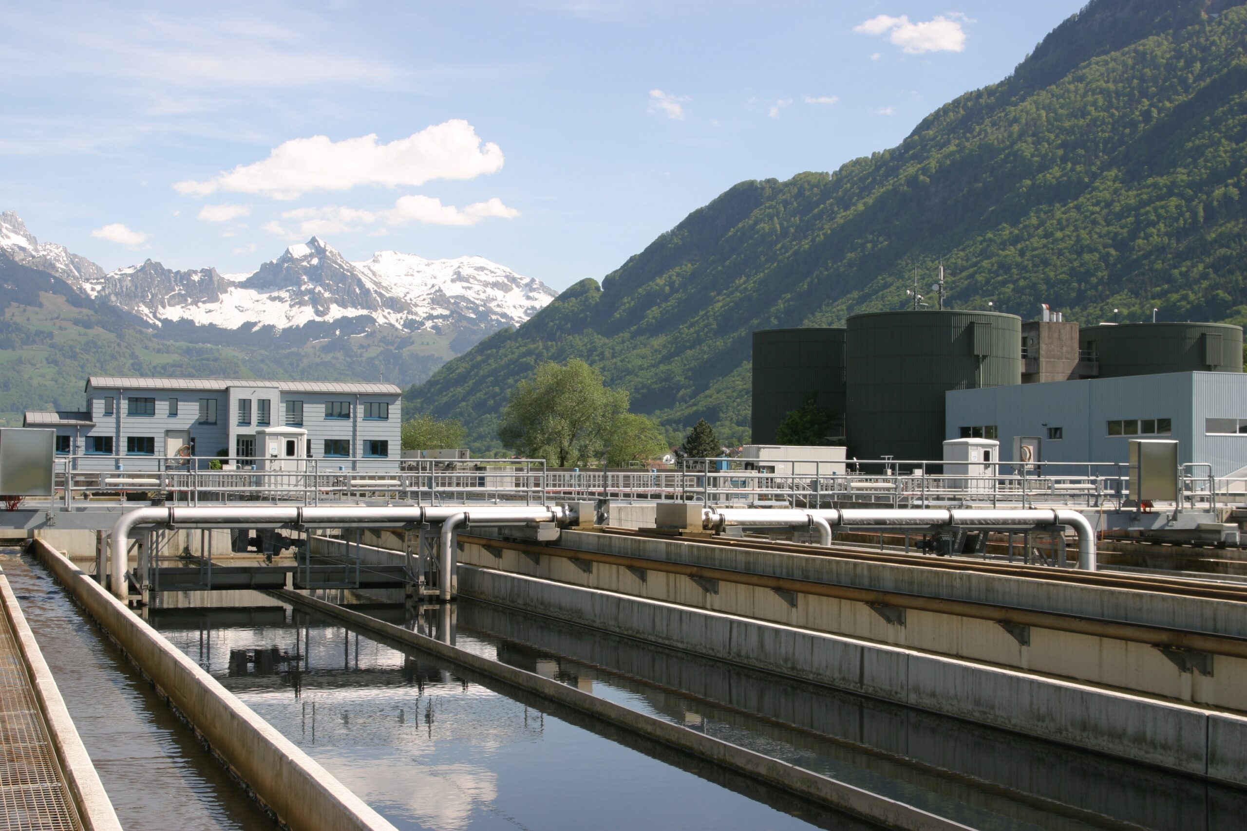 Municipal water treatment facility with settling basins, pipelines, and storage tanks surrounded by mountains