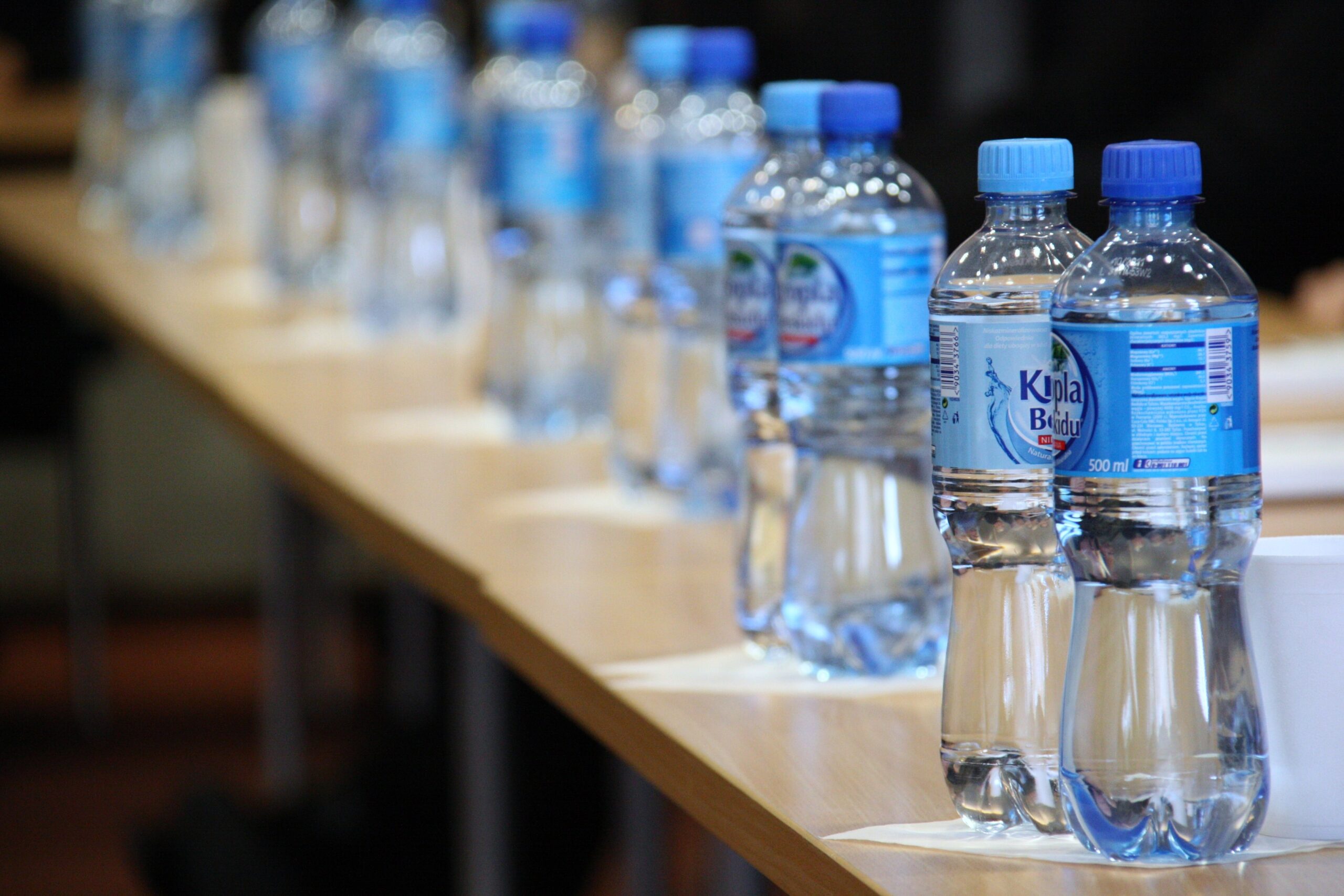 Row of sealed water bottling products with blue caps lined up on a table showing finished bottled water ready for distribution
