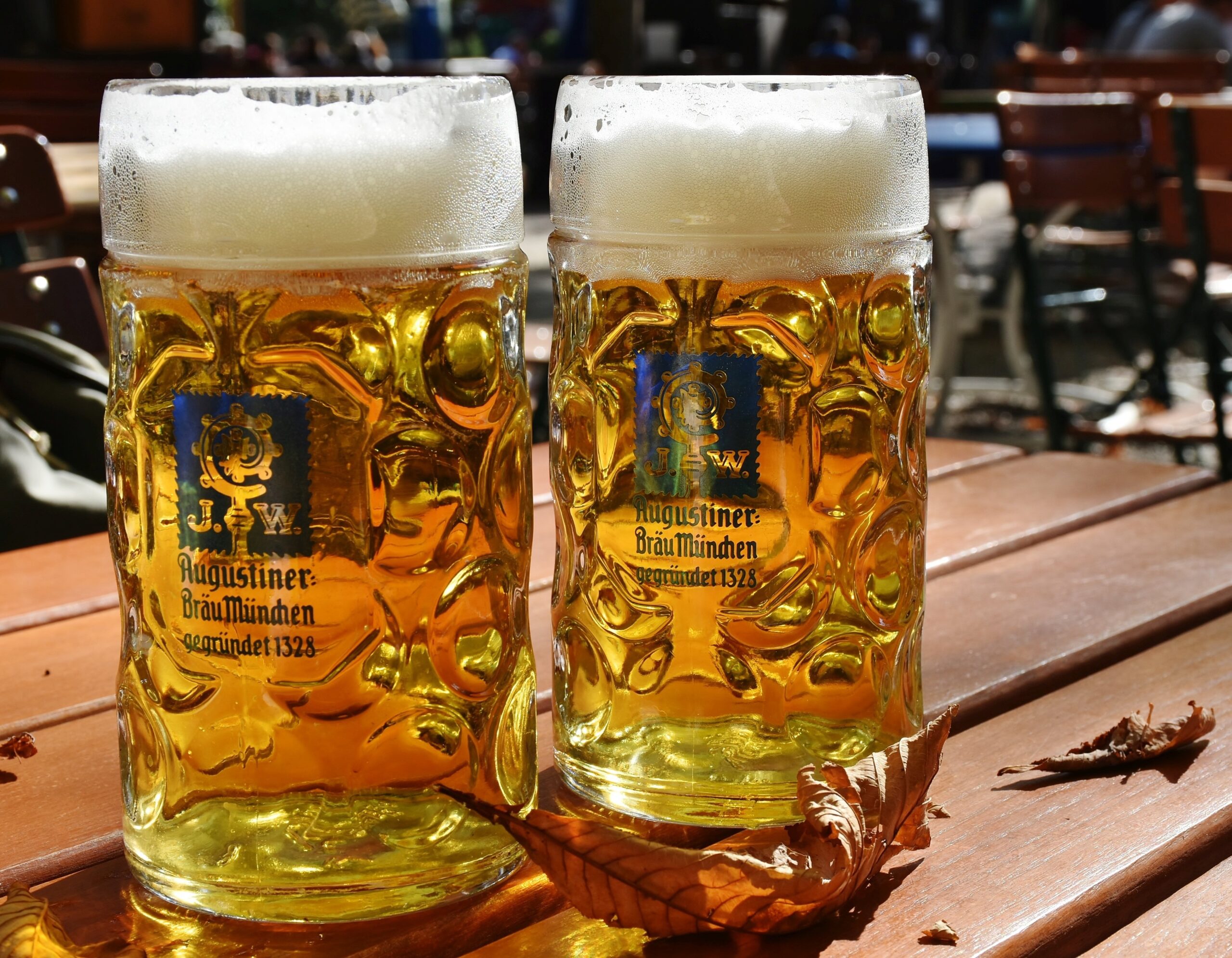 Two golden lagers with thick foam heads in glass steins on an outdoor table showcasing the result of quality brewing water