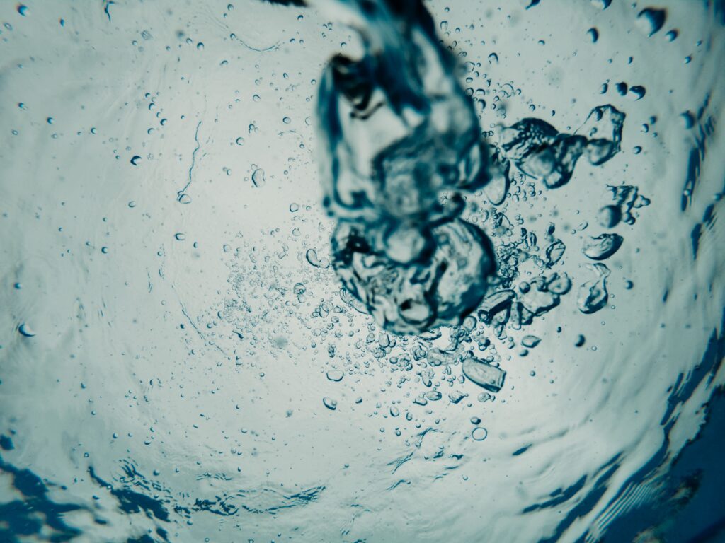 Close-up of large air bubbles rising through clear water.